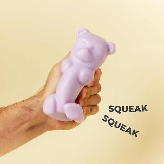 Lilac Bear Dog Toy Being Squeezed to Demonstrate High Pitched Squeaker Feature